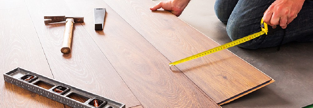 Person misst Laminat mit Zollstock